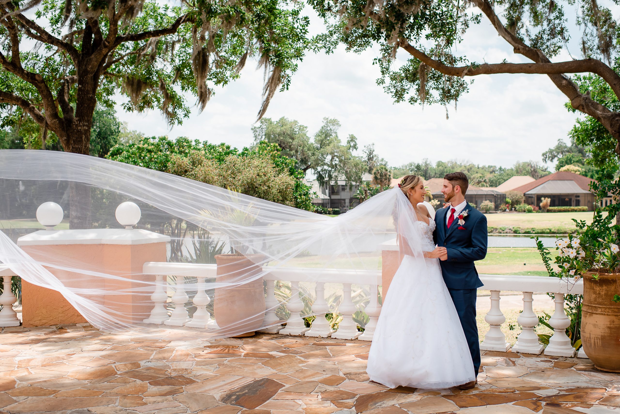 Bride and Groom Outside with Flowing long Vail and trees in the background in front of a golf course on a sunny day at La Cita in Titusville
